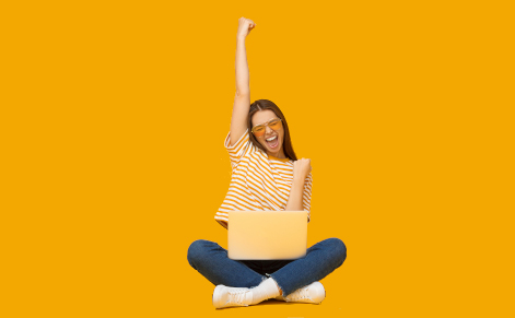 Photo of an exultant woman sitting cross legged with a laptop