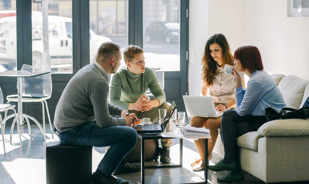 Photo of a four person business meeting around a coffee table