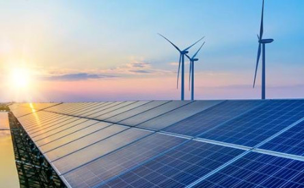 Photo of a bank of solar panels and three wind turbines